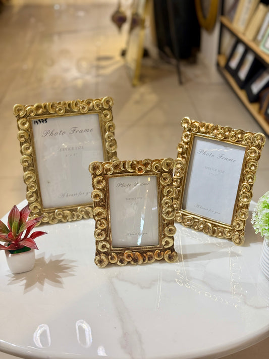A set of three golden resin photo frames in small, medium, and large sizes featuring ornate baroque carvings, displayed at Fatima Home Décor in Islamabad.
