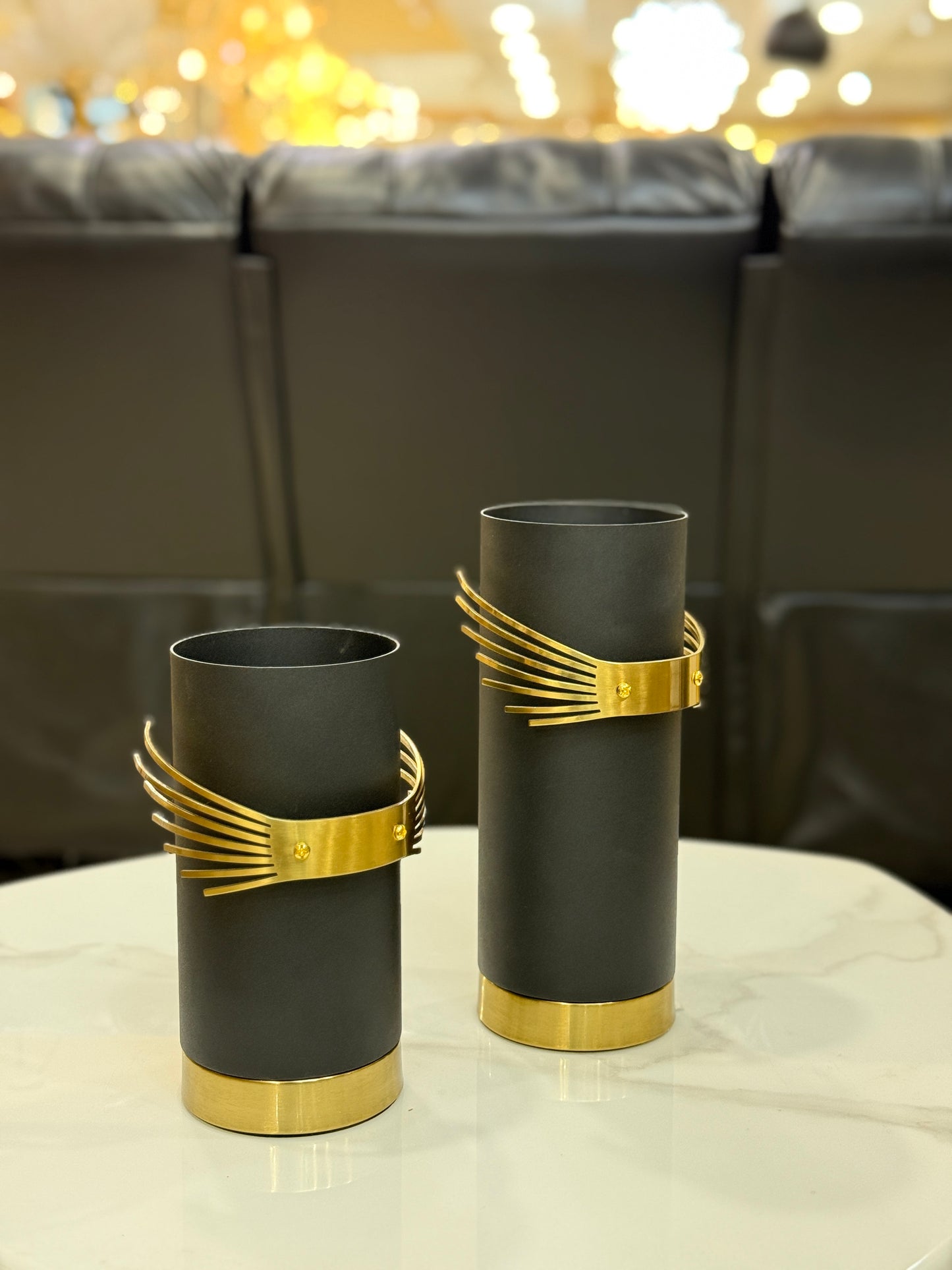 Set of two matte black metal vases with polished golden winged accents and gold bases at Fatima Home Décor store in Islamabad.
