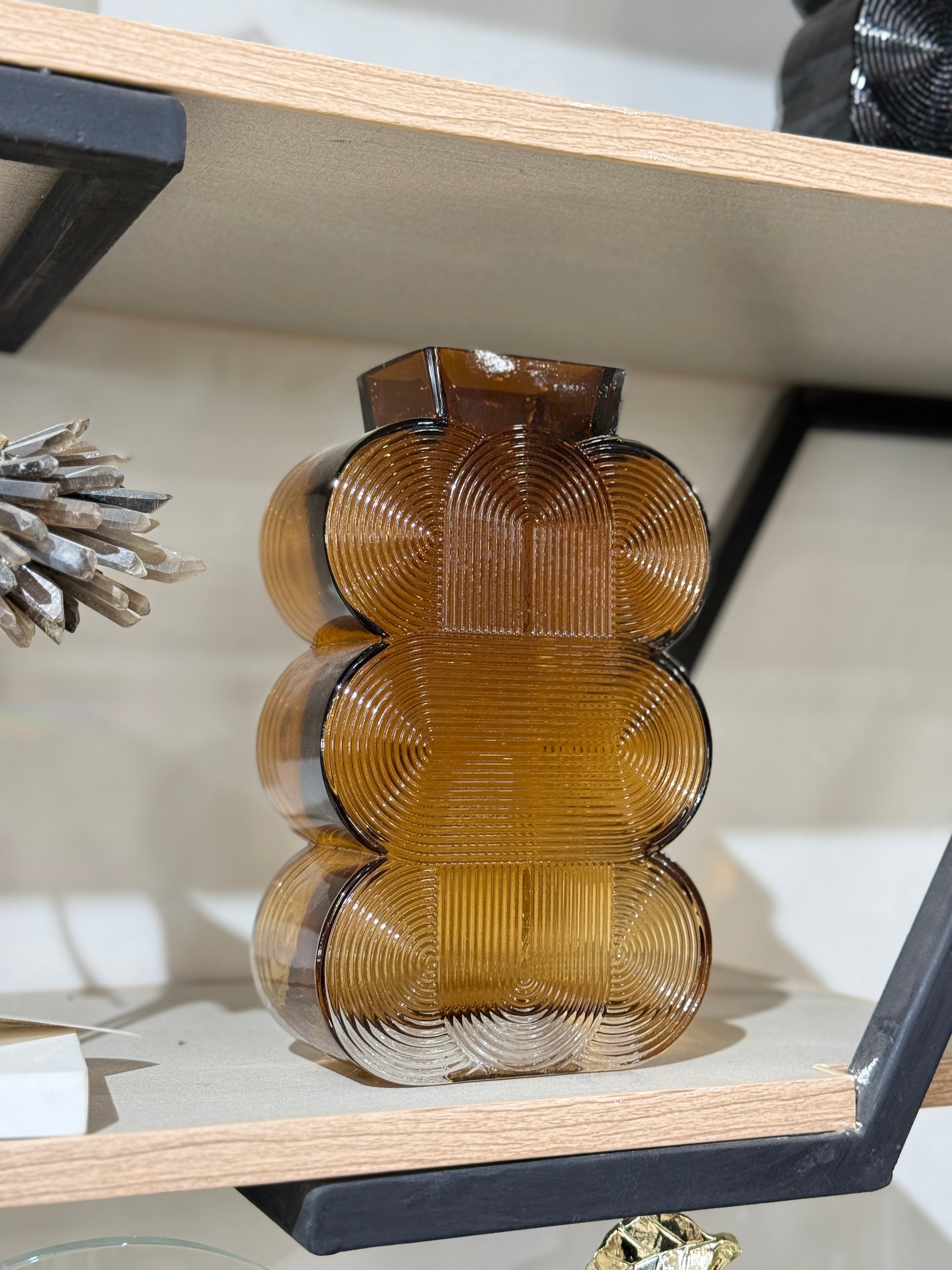 Amber-tinted tiered geometric glass vase with fine ribbed texture displayed on a wooden shelf at Fatima Home Décor store in Islamabad.