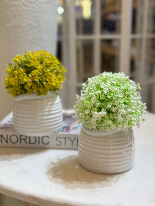 Small artificial flowering shrub with green and white petals in a white horizontal ribbed pot displayed at Fatima Home Décor store in Islamabad.