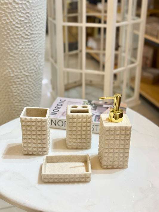 4-piece studded sandstone bathroom accessory set with gold soap dispenser pump on a marble table at Fatima Home Decor.