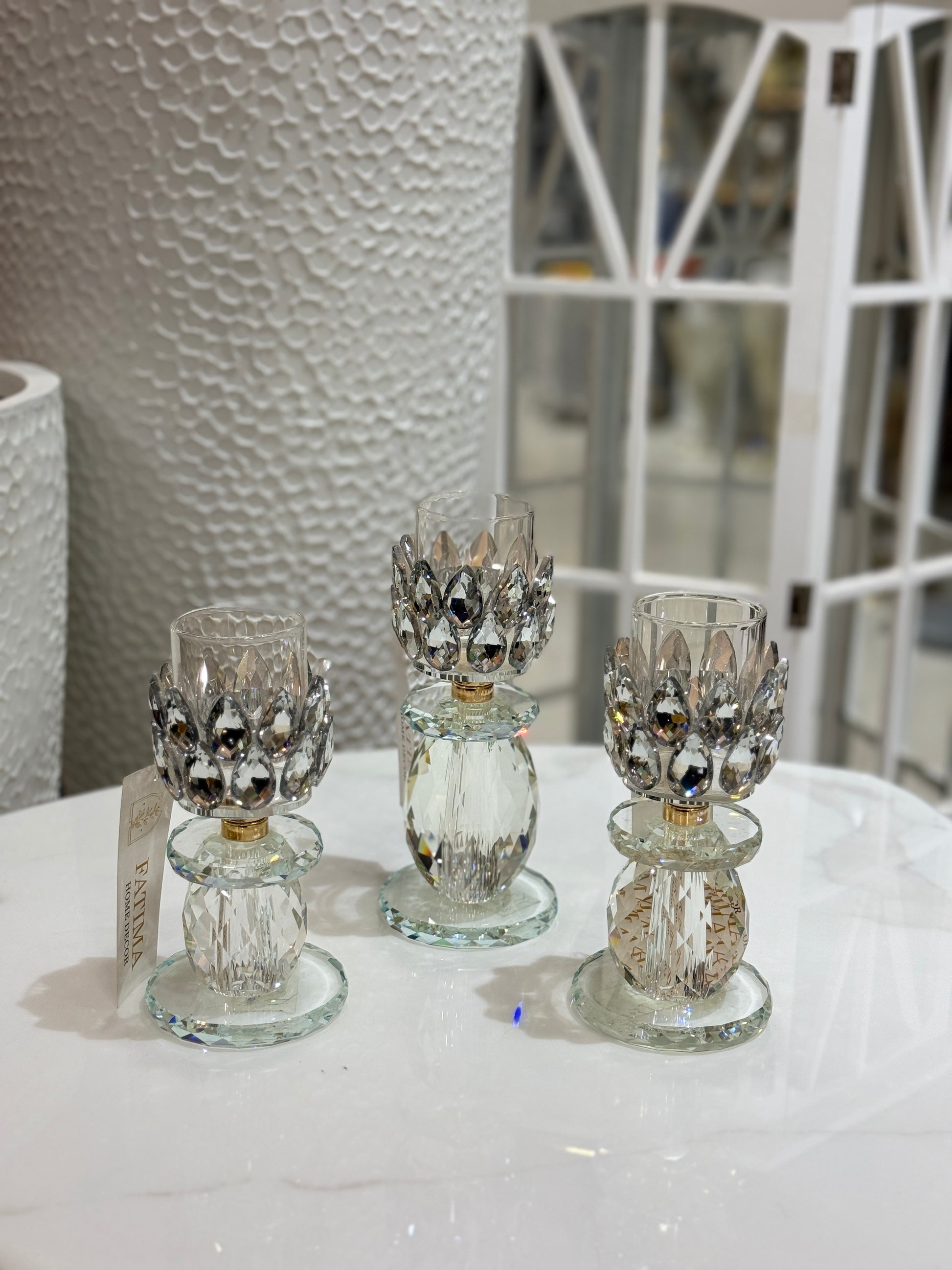Set of three crystal lotus-shaped tealight candle holders with tiered faceted bases displayed at Fatima Home Decor store in Islamabad.