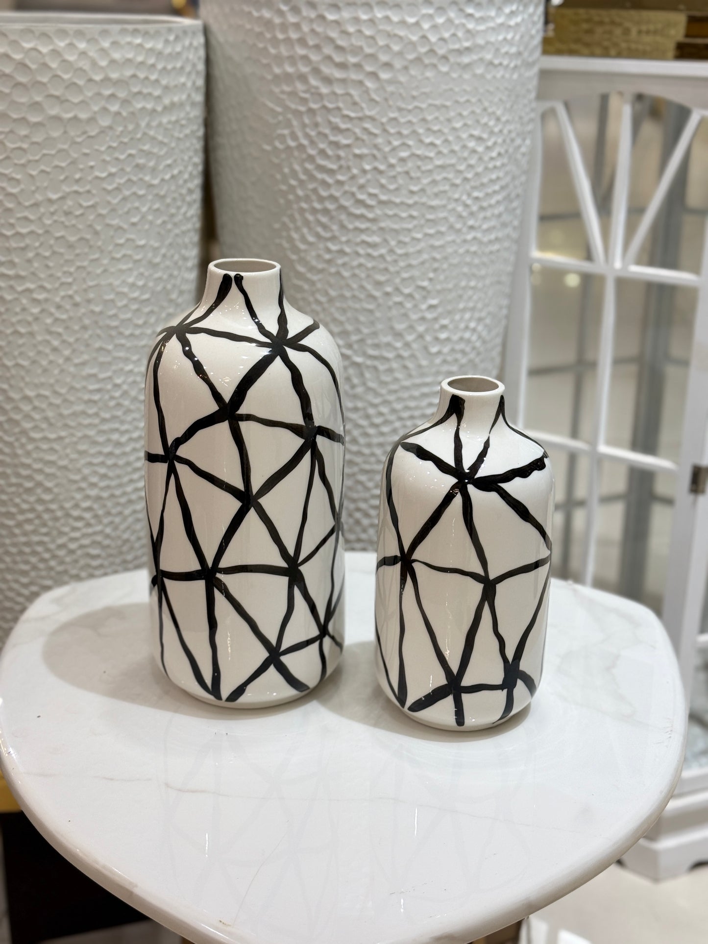 Set of two white ceramic vases with black geometric hand-painted patterns displayed at Fatima Home Décor store in Islamabad.