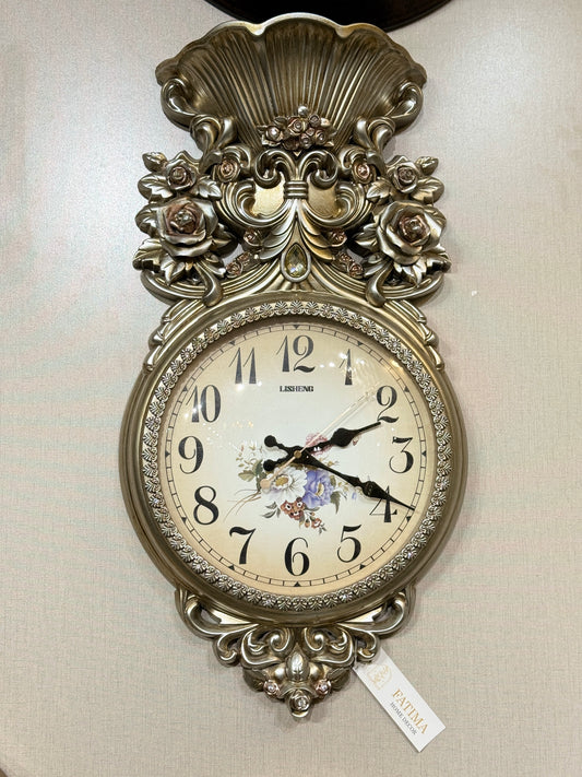 Ornate Lisheng champagne gold PVC wall clock with 3D rose carvings and floral dial displayed at Fatima Home Décor store in Islamabad.