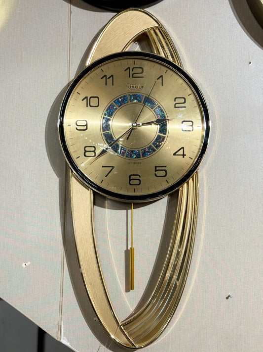 Modern Oxour golden pendulum wall clock with a brushed gold oval frame and iridescent dial accent at Fatima Home Décor store in Islamabad.