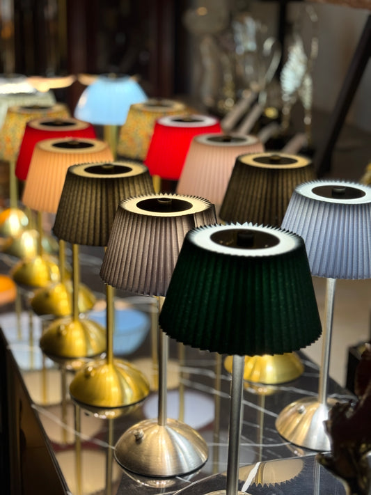 Row of colorful rechargeable cordless touch lamps with pleated shades and metallic bases at Fatima Home Décor store in Islamabad.